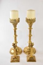 A pair of Gothic style ecclesiastical altar sticks with candles, height 48m and a pair of modern