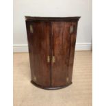 A late George III mahogany bowfront hanging corner cupboard, height 103cm.