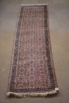 A Caucasian hand woven wool runner, worked with an all over floral design against a red ground,