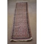 A Caucasian hand woven wool runner, worked with an all over floral design against a red ground,