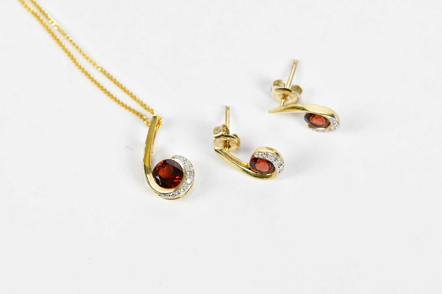 A 9ct yellow gold garnet and diamond chip swept pendant on fine link chain, with a pair of