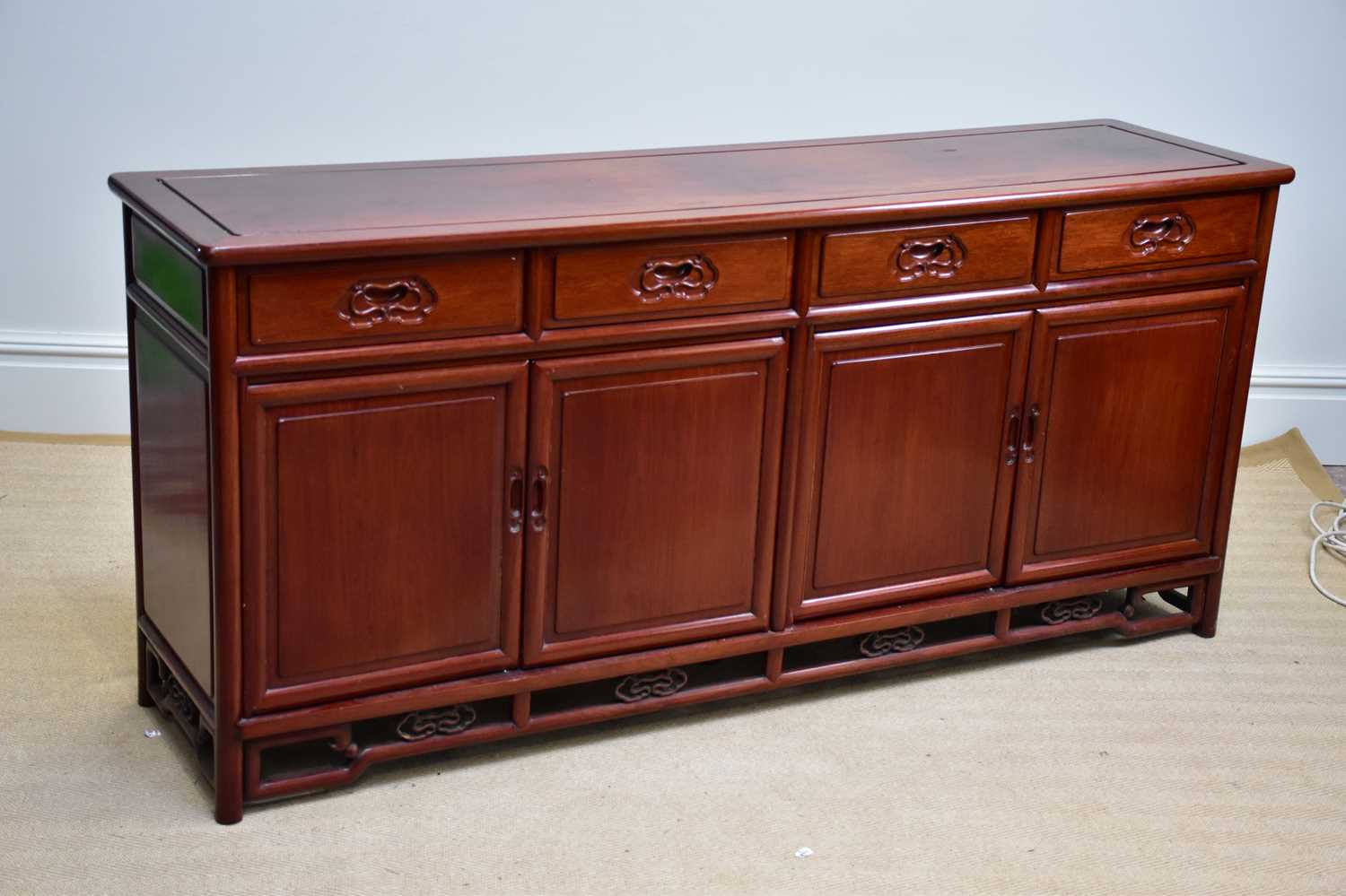 A 20th century Chinese rosewood sideboard with four drawers above four panelled cupboard doors,