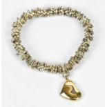 A multi link white metal bracelet set with 9ct yellow gold heart shaped pendant drop.