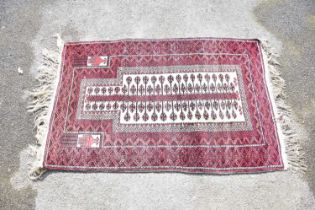 A Middle Eastern rug with central lozenge and floral decoration on red ground, 148 x 60cm.