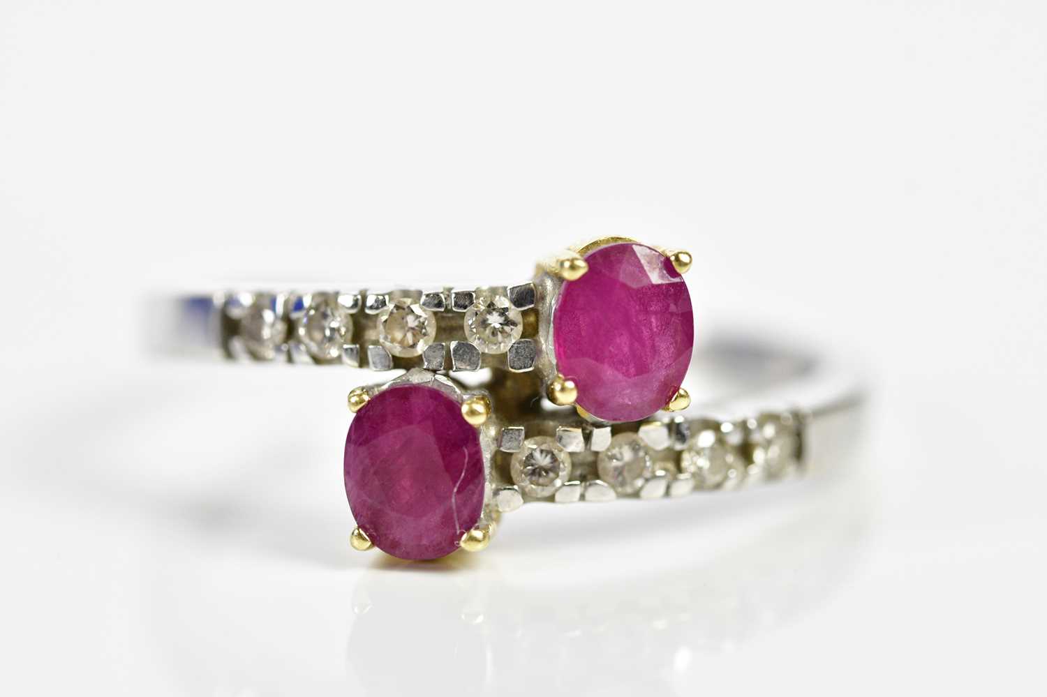 An 18ct white gold ruby and diamond crossover designed ring, size T 1/2, approx. 4.96g.