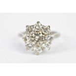 An 18ct white gold and floral cluster ring, the central round brilliant cut stone weighing approx.