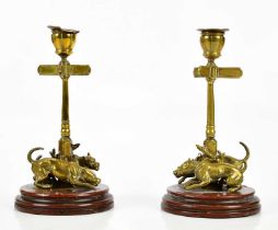 A pair of late 19th century bronze candleholders, modelled as dogs tied to a street post, on