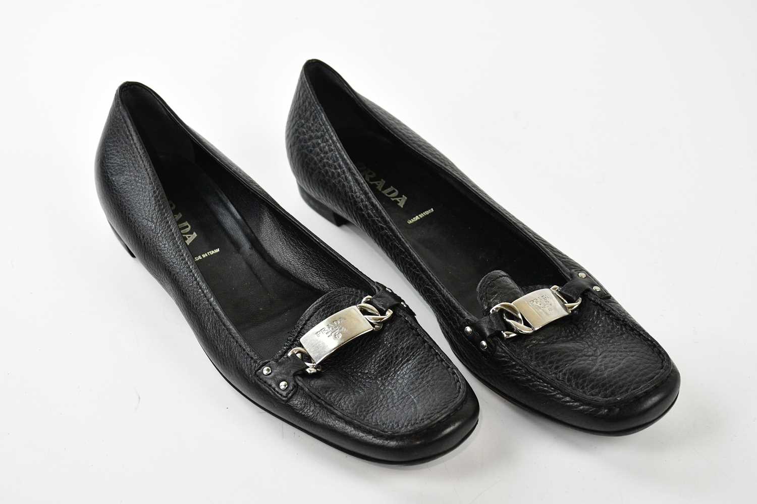 PRADA; a pair of black pebbled leather flat court shoes, embellished with silver tone buckle with