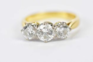 An 18ct yellow gold three stone diamond ring, the central round brilliant cut stone weighing