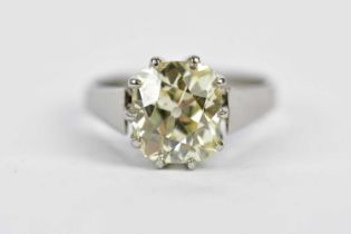 A white metal diamond solitaire ring, the claw set cushion cut diamond weighing over 3cts, with