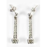 A pair of 18ct white gold diamond drop earrings, the channels set with eight tapering round