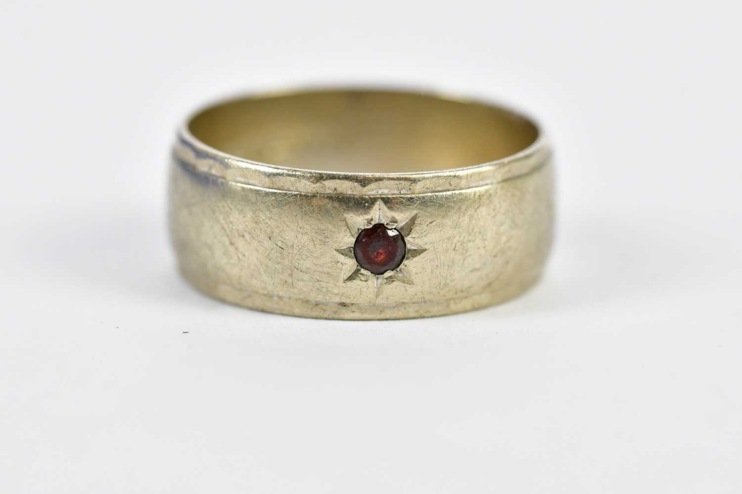 A 9ct white gold wedding band set with single dark ruby, size T 1/2, approx 5.94g.