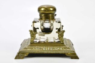 A 19th century brass desk stand housing a large cut glass inkwell with brass hinged cover, width