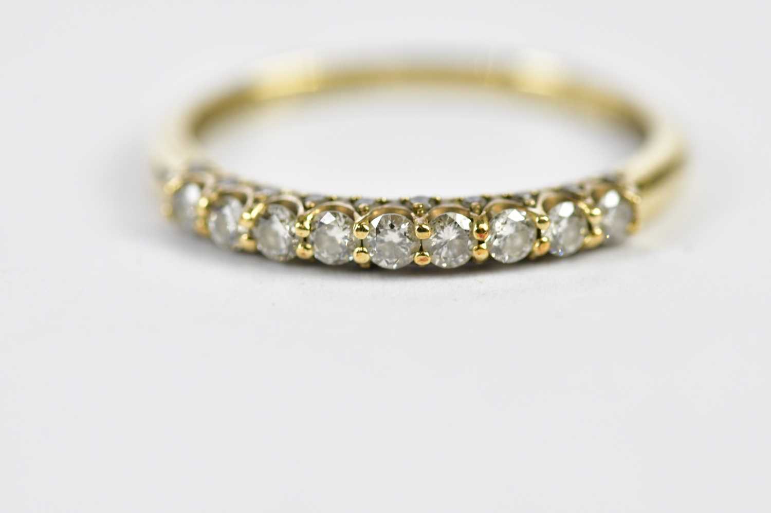 A 9ct yellow gold half eternity ring, set with nine principle stones and a melee of twnety stones,