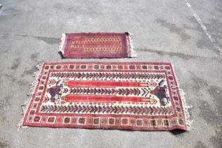 An Eastern rug decorated with stylised motifs and symbols on a red and cream ground, 208 x 110cm,