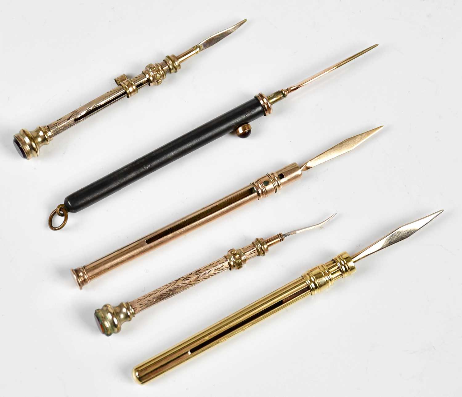 Four late 19th/early 20th century yellow metal tooth picks, including an example with cast linear