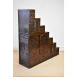 A Chinese stained pine cabinet of stepped form with an arrangement of sliding and cupboard doors and