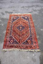 A large Eastern style rug with stylised decoration with symbols on an orange and red ground with