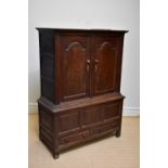 An 18th century oak livery cupboard, with two arched panelled doors, on base with two short drawers,