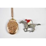 A paste horse and jockey brooch and a 9ct yellow gold chain supporting an oval front and back locket