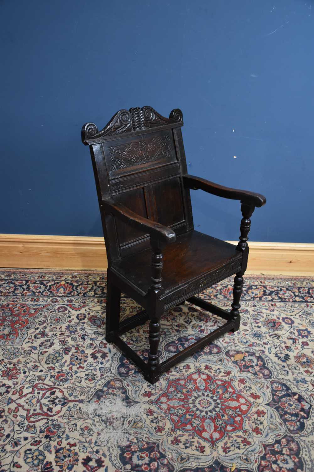 An 18th century and later oak wainscot type chair with carved back and single plank seat, on block