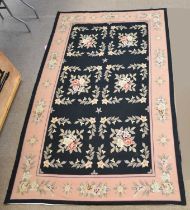 A tapestry carpet, worked with floral motifs against a black ground, 260 x 158cm. Condition