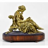 A late 19th/early 20th century gilt bronze figure of a seated lady reading, on oval wooden plinth