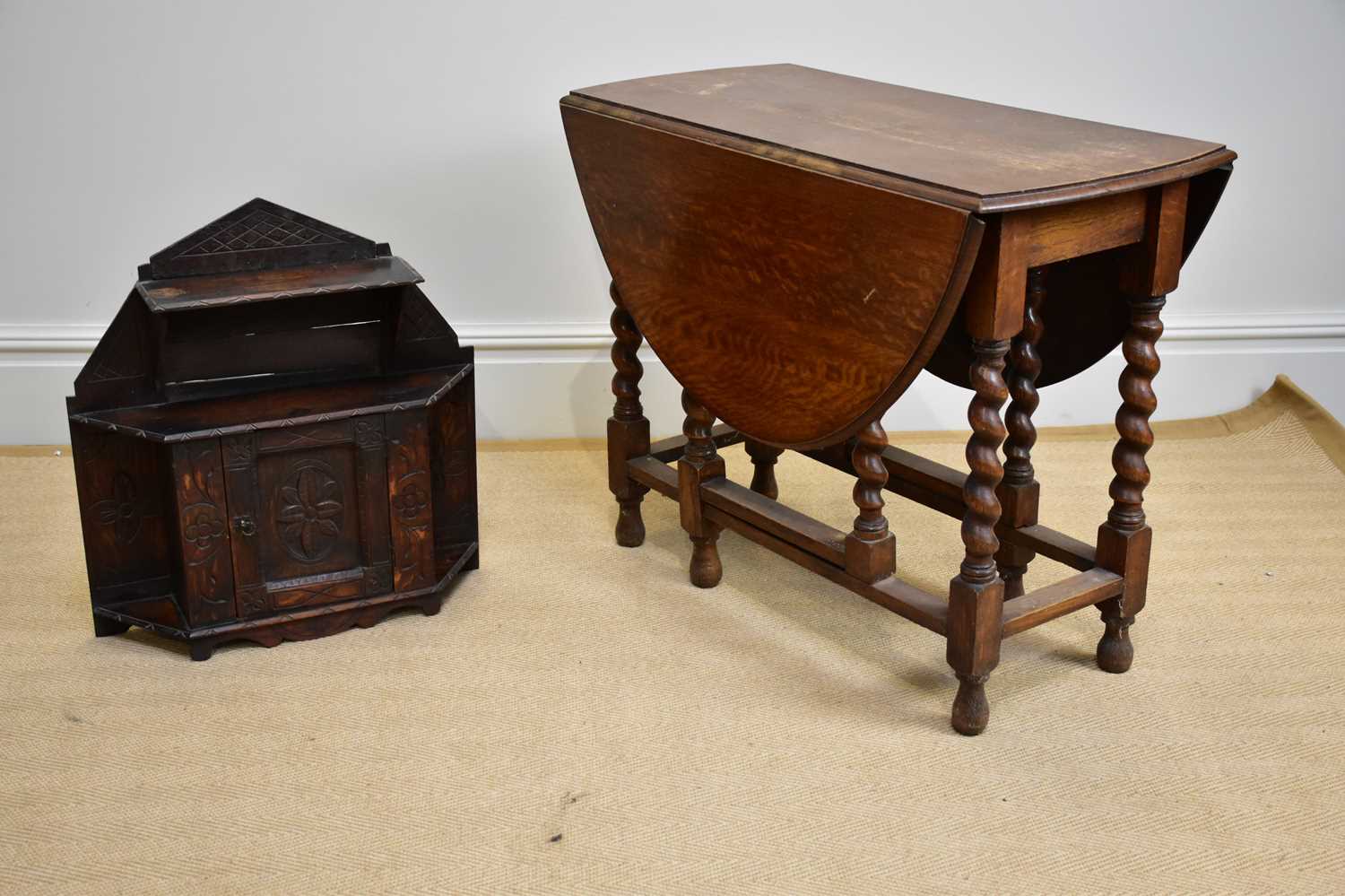 A 1920s oak drop-leaf gateleg dining table, width 86cm, height 72cm, and a carved oak hanging