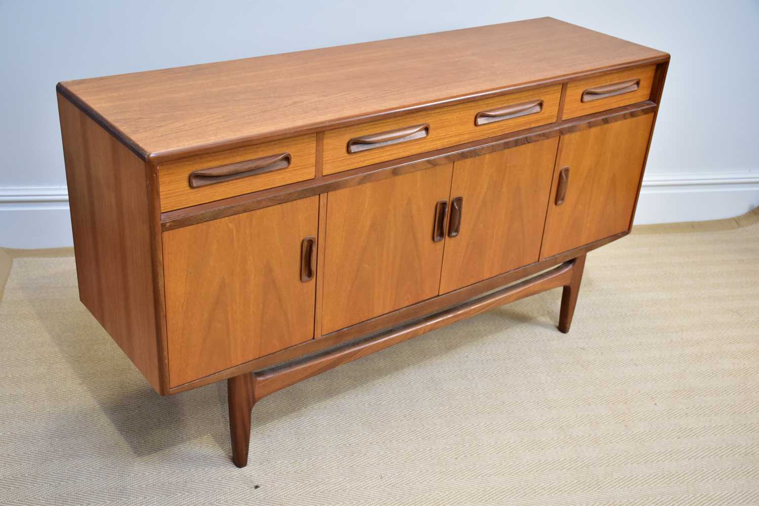 G-PLAN; a 'Fresco' range teak sideboard with three drawers above four panelled cupboard doors, on