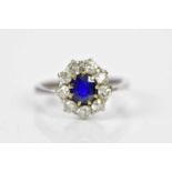 An 18ct white gold sapphire and diamond oval flower head ring centred with a claw set oval