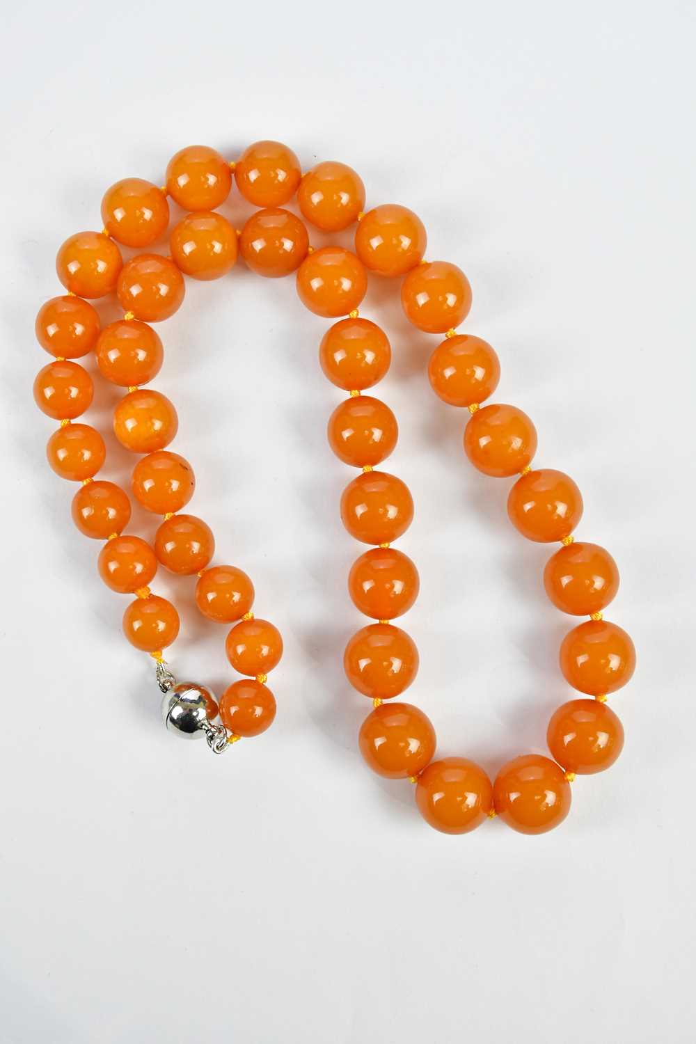 A cherry amber coloured beaded necklace, with silvered bead clasp, approximate weight 67g.