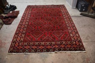 A modern red ground rug with central geometric pattern, 305 x 205cm. Condition Report: Carpet