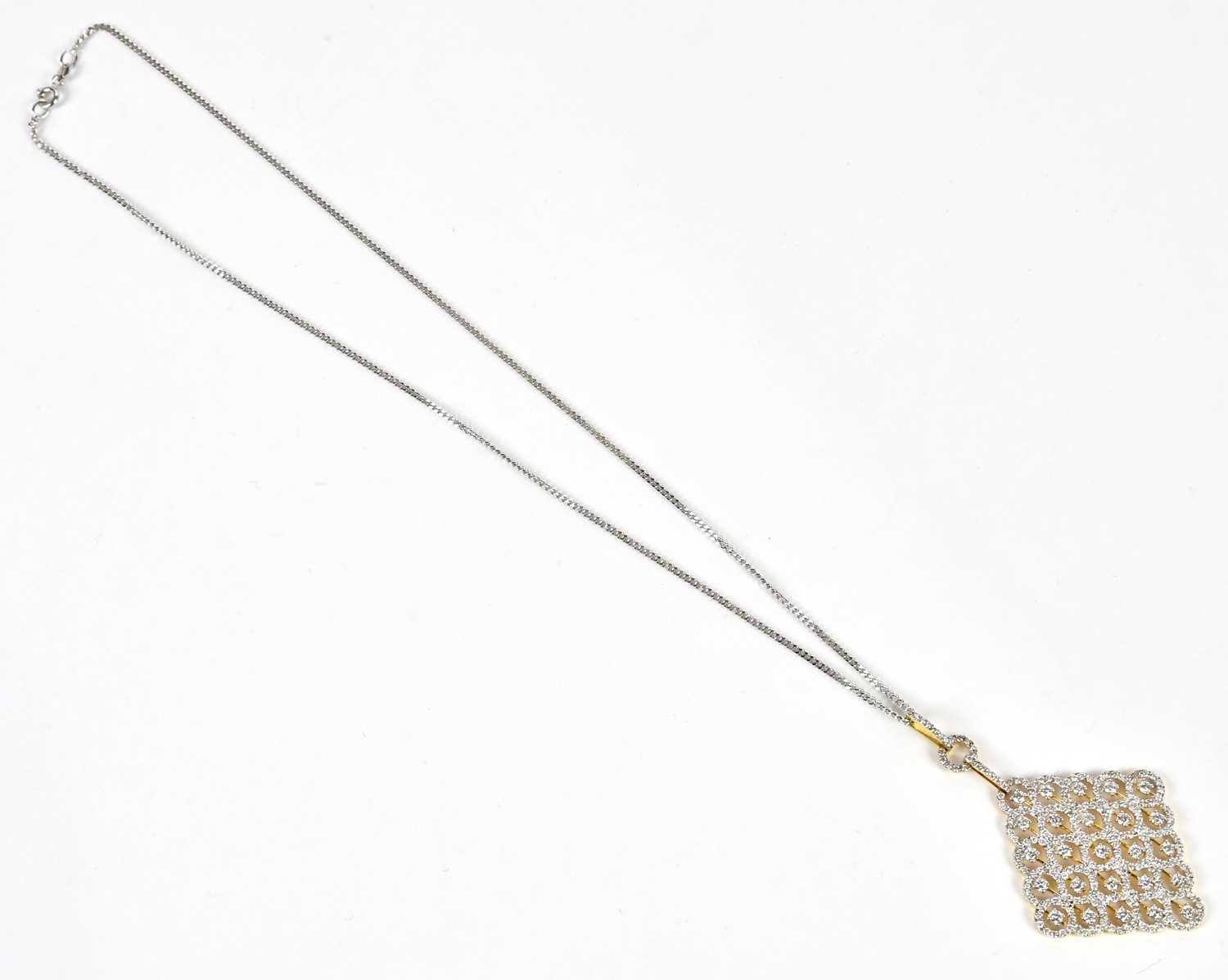 An 18ct yellow and white gold pierced diamond set lozenge shaped pendant, suspended on a 9ct white