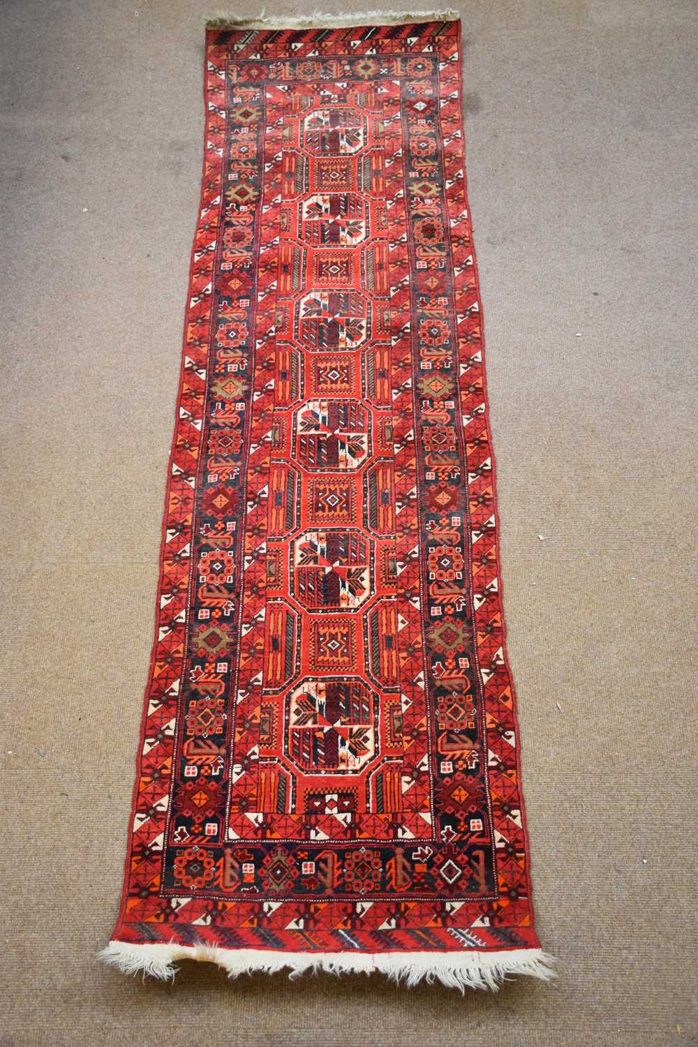 A Caucasian hand woven wool runner, worked with geometric detailing against a red ground, 355 x