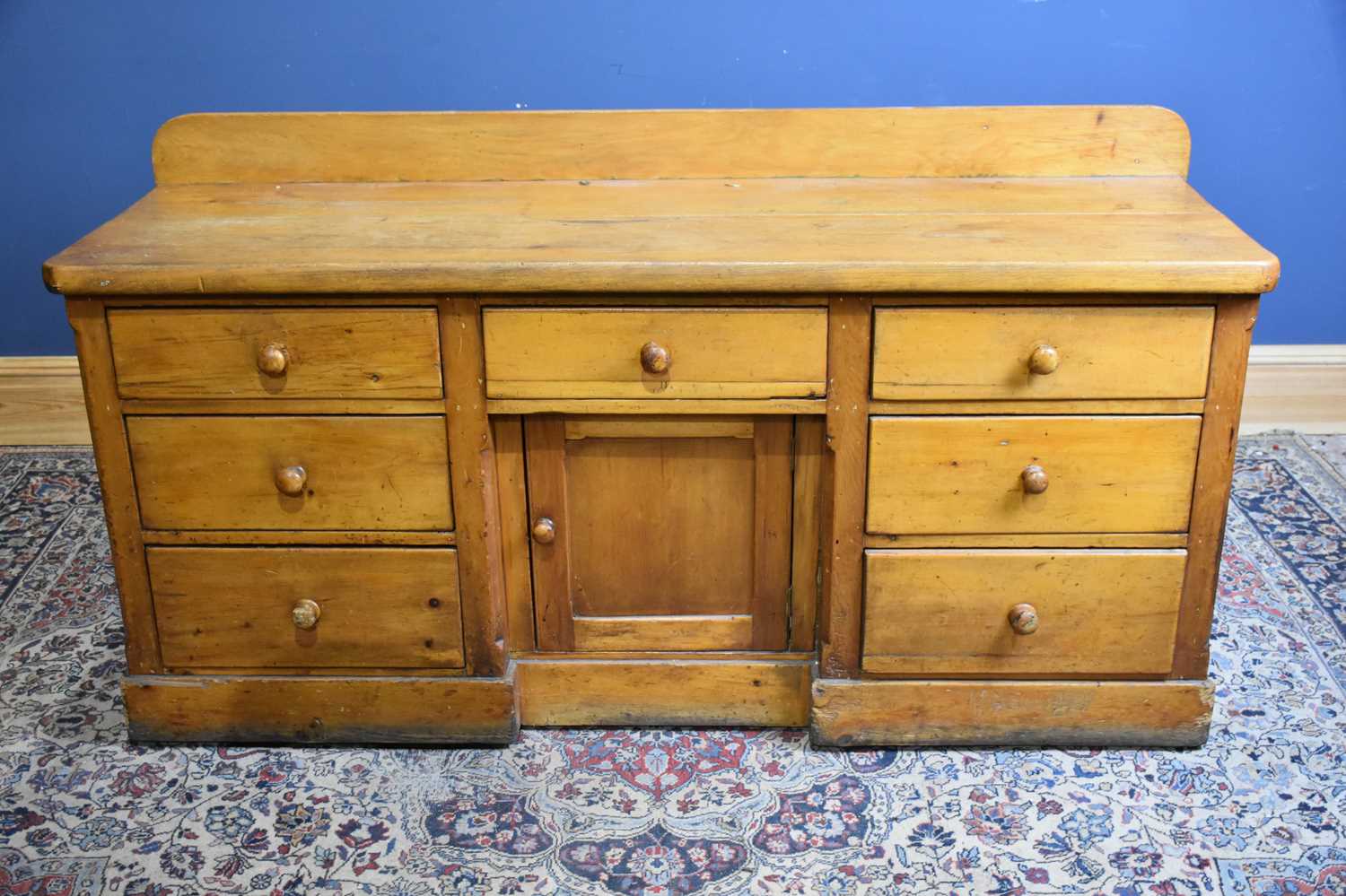 A Victorian pine dresser base with an arrangement seven drawers and panelled cupboard door on plinth