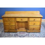 A Victorian pine dresser base with an arrangement seven drawers and panelled cupboard door on plinth