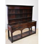 An 18th century oak dresser with plate rack back, the moulded cornice above the boarded back and two