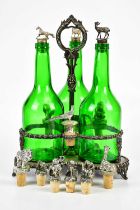 An early 20th century silver plated bottle stand with three green glass associated bottles with cast