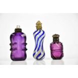 Two Victorian amethyst coloured perfume bottles, one example with white metal stopper, and a late