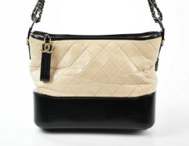 CHANEL; a cream and black quilted calfskin 2018 Gabrielle crossbody bag with gold tone and antique