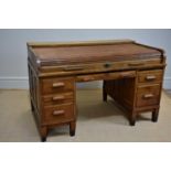 An early 20th century roll-top knee-hole desk with an arrangement of six drawers on block legs, with