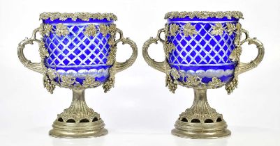 A pair of plated urns decorated with fruiting vines, with blue glass liners, height 34cm.