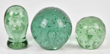 Three Victorian green glass dump weights, including an example with internal floral decoration,