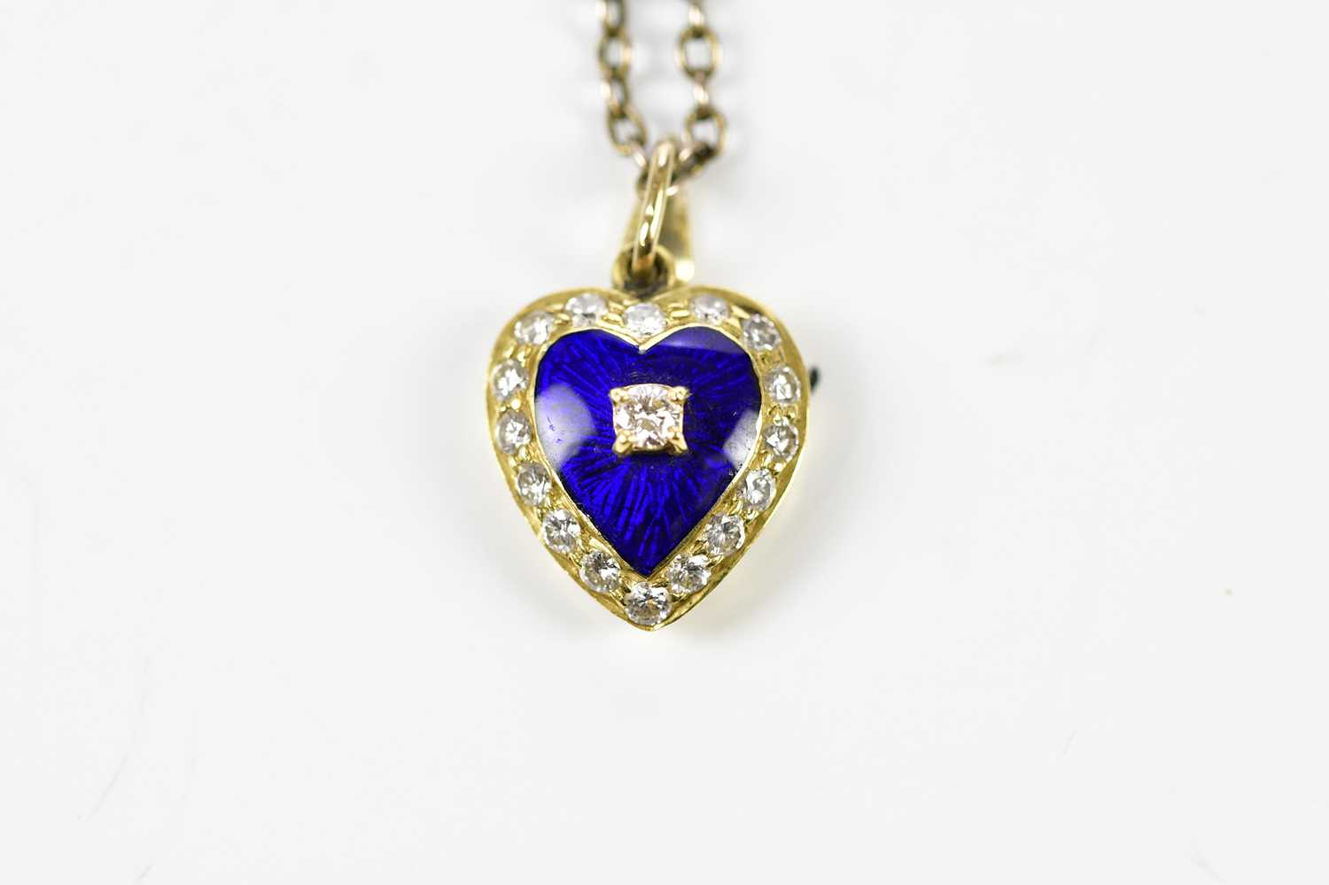 An 18ct yellow gold heart shaped pendant centred with a round brilliant cut diamond on a blue