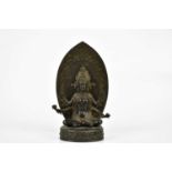 A Chinese bronze figure of a female deity with four arms, with leaf shaped back plate and oval base,