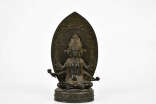 A Chinese bronze figure of a female deity with four arms, with leaf shaped back plate and oval base,