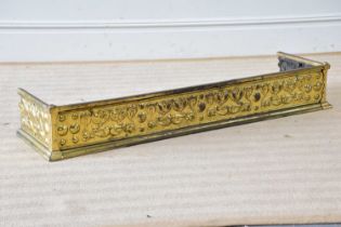 An Art Nouveau brass fender with embossed scrolling and floral decoration, length 129cm.