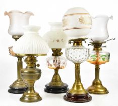 A collection of late Victorian and later oil lamps to include an example with frosted glass shade