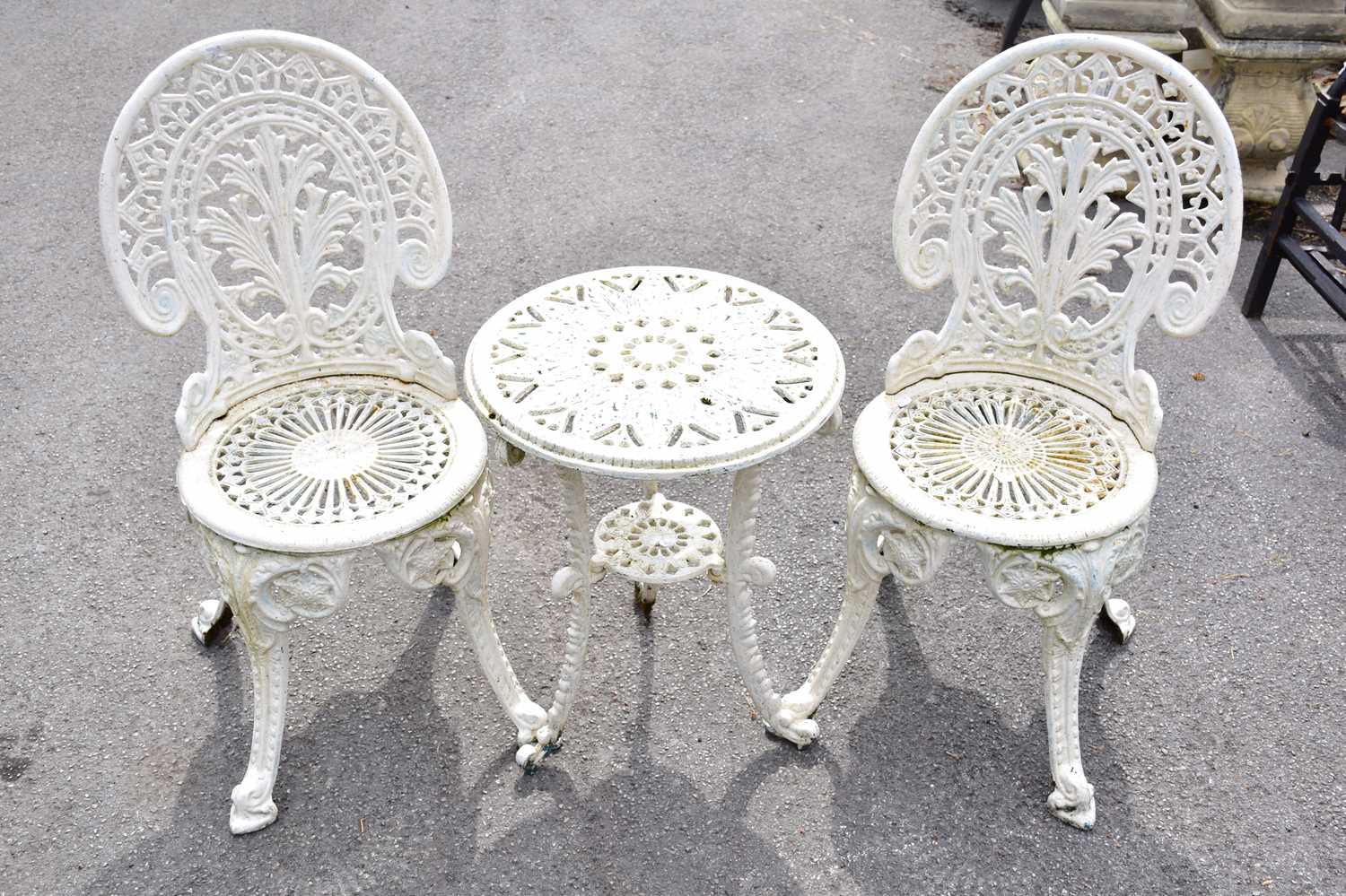 A pair of white painted cast iron chairs and a similar table (3).