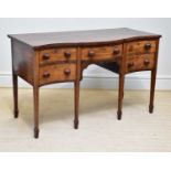 A late George III serpentine mahogany sideboard with three short drawers and one deep drawer on